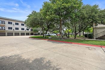 A parking lot with trees and a building in the background